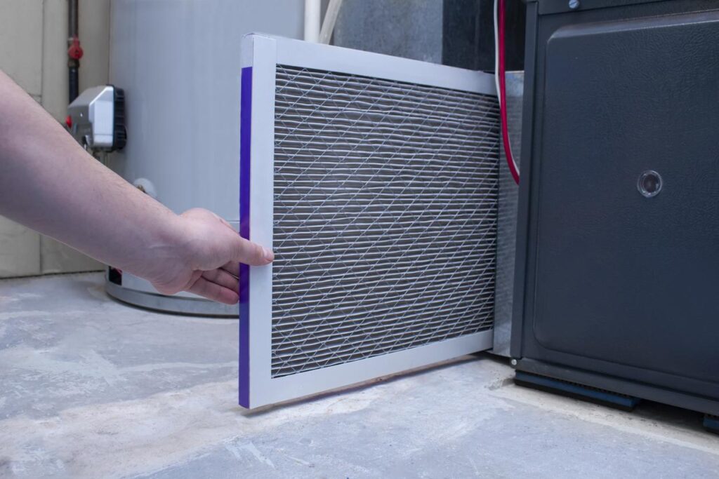 An HVAC technician changing the air filter on a home furnace.