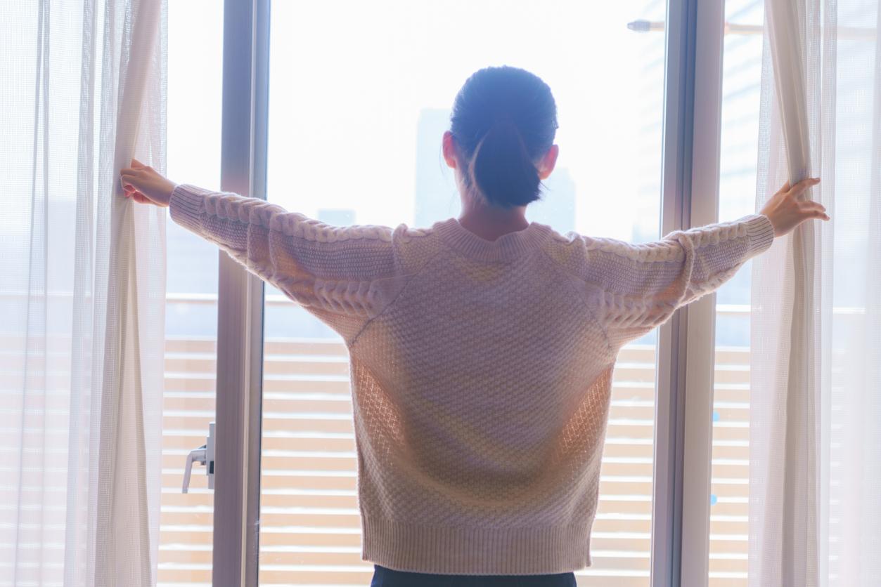 A young woman opened her curtains to get natural sunlight